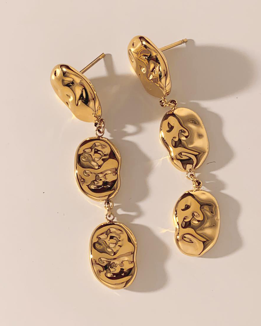Lilyah Jewelry's Gold plated earrings on a beige background. They look like drops, three golden drops falling.