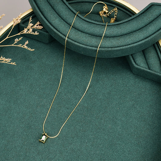 A gold-plated pendant necklace with a princess cut inlay, displayed on a green cushion. Lilyah Jewelry Gold Plated Necklace. Gift Ideas for her.