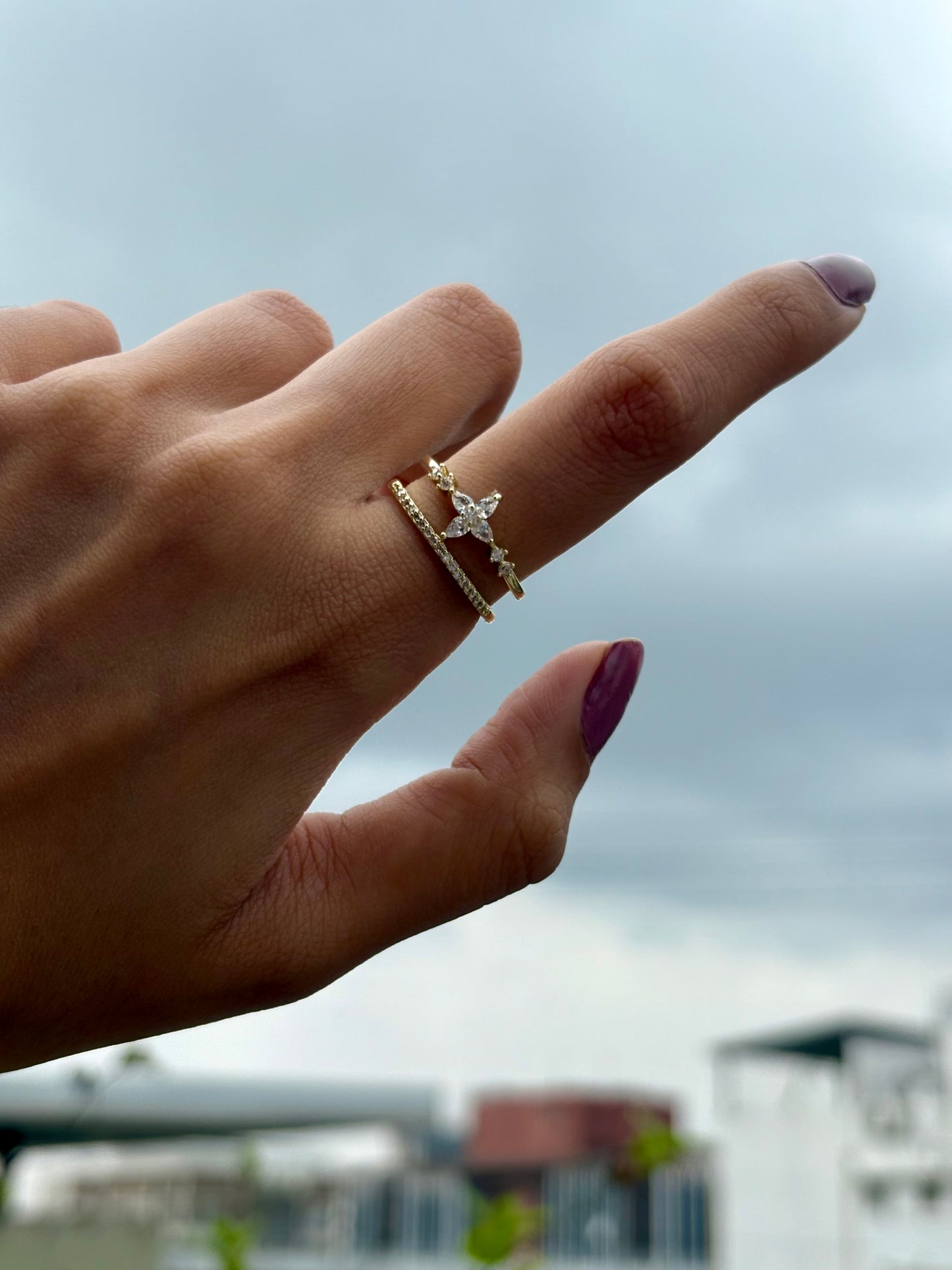 Lilyah Jewelry Gold Plated Zircon Diamond Ring.  Two layers and adjustable promise ring. Hand wearing a gold ring with a diamond against a blurred outdoor background