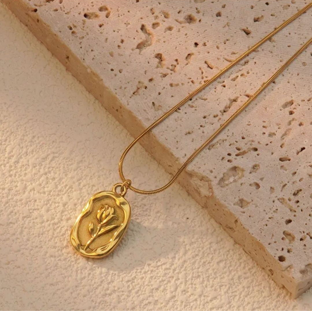 Lilyah Jewelry Necklace. Gold plated necklace with a pendant on a textured beige surface