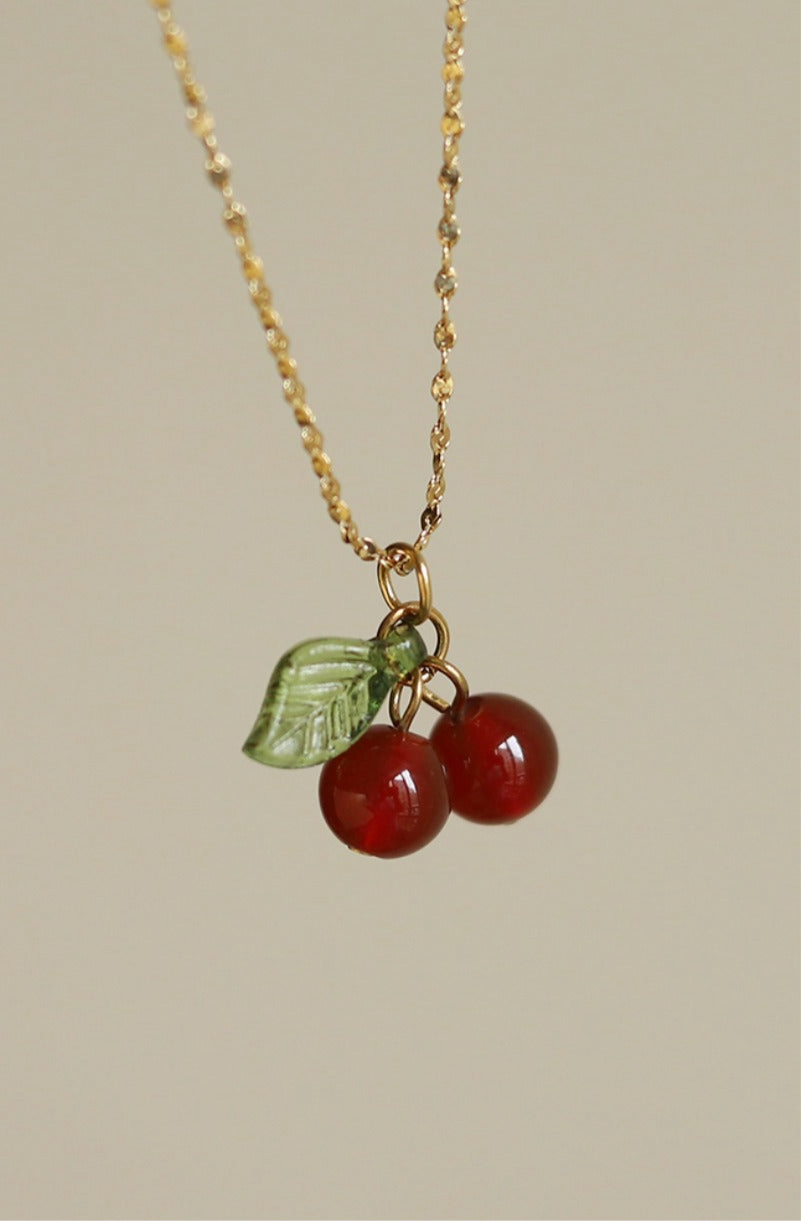 Lilyah Jewelry gold plated Necklace with cherry and leaf charm on a beige background