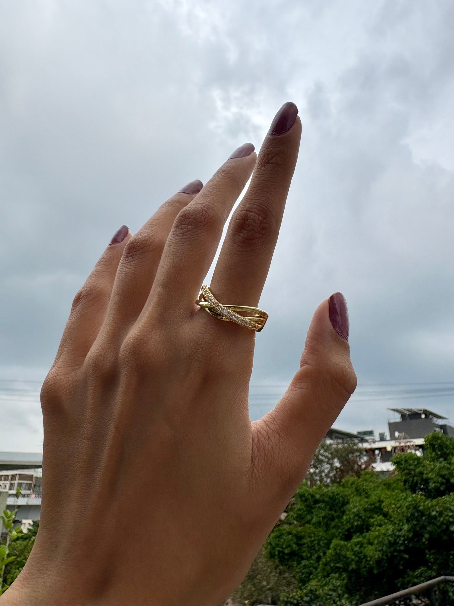 Lilyah Jewelry Gold Plated Zircon Diamond Ring. adjustable promise ring. accents of gold and diamonds. Hand wearing a gold ring with a cloudy sky in the background
