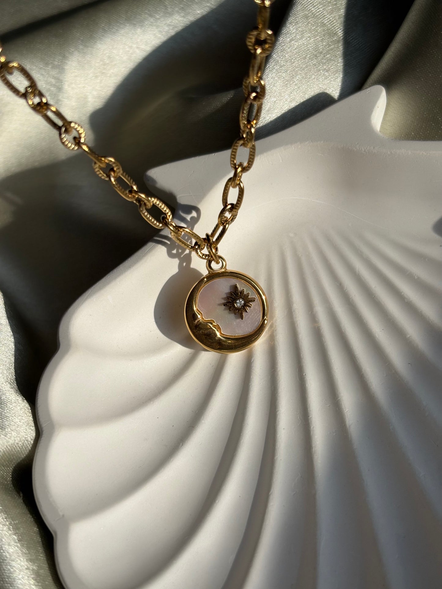 Lilyah Jewelry gold plated Necklace with a pendant of half moon and a star on a white shell background.
