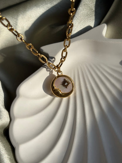 Lilyah Jewelry gold plated Necklace with a pendant of half moon and a star on a white shell background.