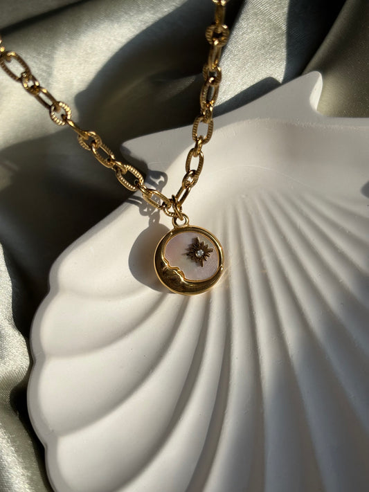 Lilyah Jewelry gold plated Necklace with a pendant of half moon and a star on a white shell background.