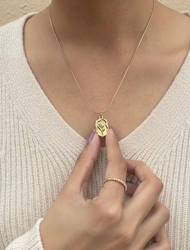 Lilyah Jewelry Necklace. Gold plated necklace with a pendant being adjusted on a person wearing a beige sweater.
