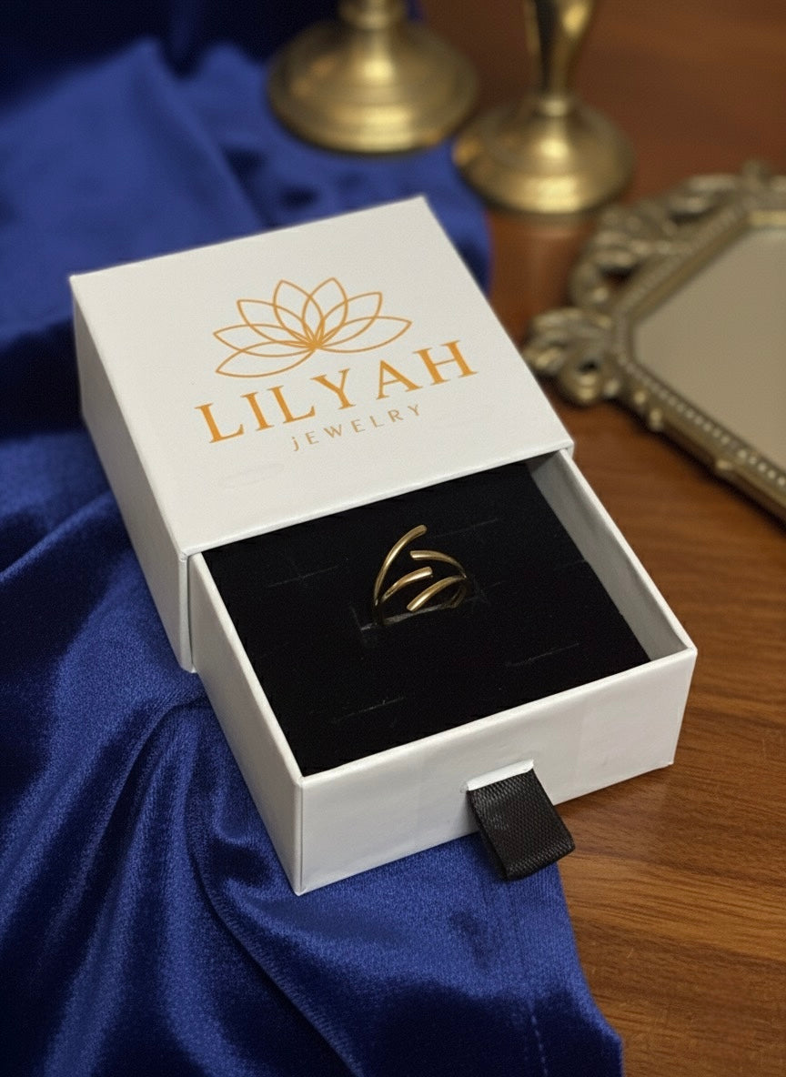 Jewelry box with a ring inside, branded 'LILYAH Jewelry', on a blue fabric background. 