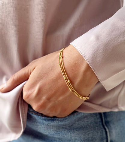 Lilyah Jewelry Gold Plated Delicate Bracelet . Stunning, minimalistic and elegant. Gift for her. A person wearing a gold-plated layered golden orbit bracelet on their wrist.