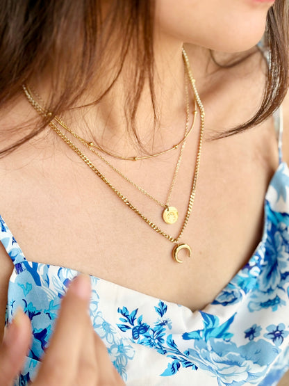 A close-up image of a woman's neck wearing a layered gold-plated necklace with a moon pendant. Lilyah Jewelry Gold Plated Necklace. Gift Ideas for her.