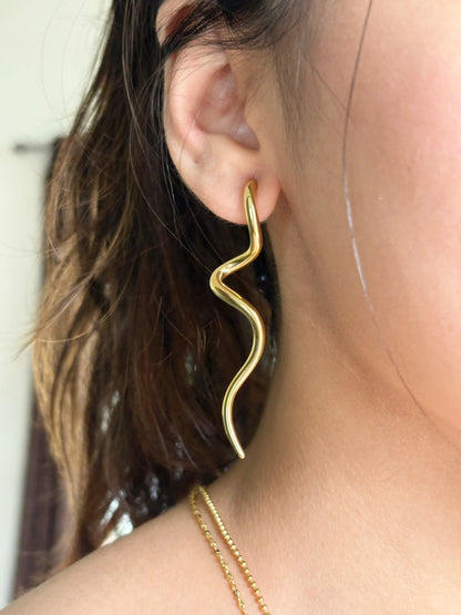 A close-up image of a woman's ear wearing a gold-plated squiggle drop earring.  Lilyah Jewelry Gold Plated Earring. Gift Ideas for her.