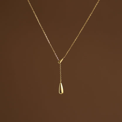 A gold-plated dainty water droplet necklace on a brown background. Lilyah Jewelry Gold Plated Necklace. Gift Ideas for her.