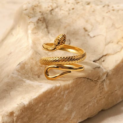 An 18k gold plated golden serpent wrap ring placed on a textured stone surface. Lilyah Jewelry Gold Plated Ring . Stunning, minimalistic, adjustable, elegant and statement ring. Gift idea for her.
