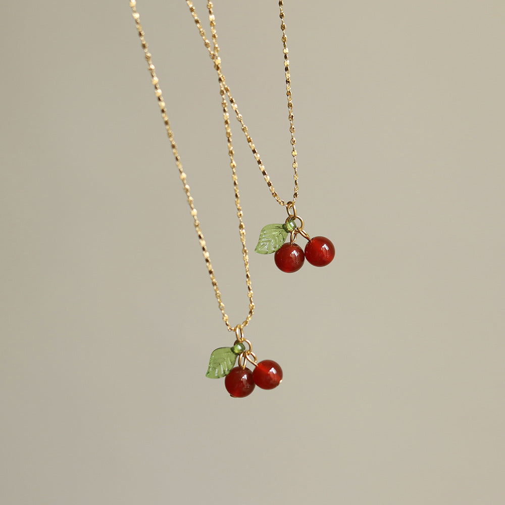 Lilyah Jewelry Necklace. Gold plated necklace with cherry pendants on a neutral background