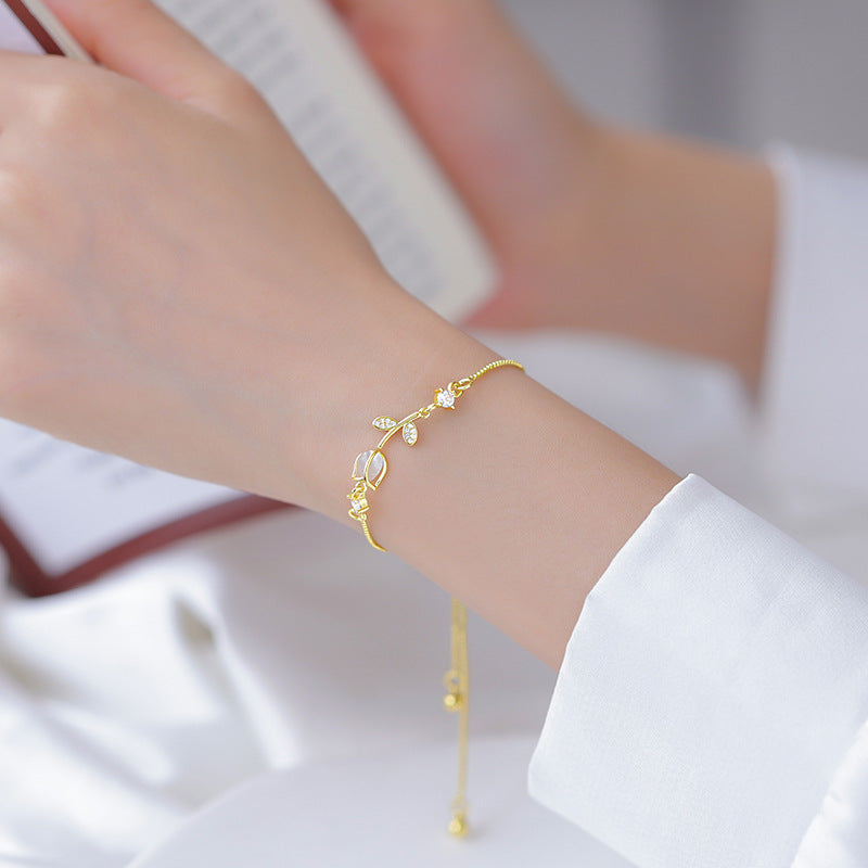 Lilyah Jewelry Gold Plated Delicate Bracelet . Stunning, minimalistic and elegant. Gift for her. A person wearing a white shirt with the sleeve rolled up to reveal a gold-plated bracelet with a tulip design on their wrist.