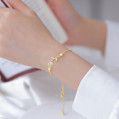 Lilyah Jewelry Gold Plated Delicate Bracelet . Stunning, minimalistic and elegant. Gift for her. A person wearing a white shirt with the sleeve rolled up to reveal a gold-plated bracelet with a tulip design on their wrist.