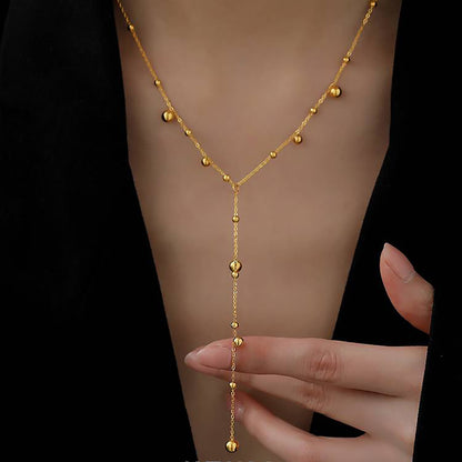 Lilyah Jewelry Gold Plated Necklace. Gift Ideas for her. An 18k gold plated delicate drop Y-necklace with small spherical pendants, displayed on a person's neck. 