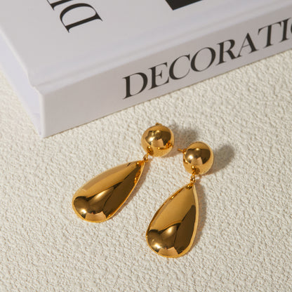 A pair of 18k gold plated teardrop-shaped drop earrings placed on a textured surface. Lilyah Jewelry Gold Plated Earring. Gift Ideas for her.