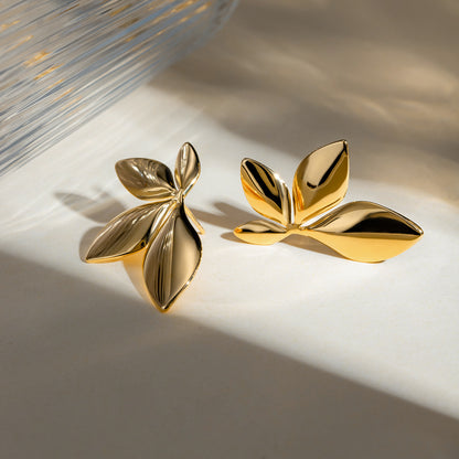 A pair of 18k gold plated floral stud earrings placed on a white surface, reflecting light on their golden surface. Lilyah Jewelry Gold Plated Earring. Gift Ideas for her.