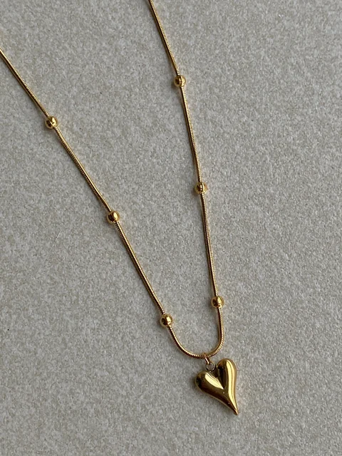 Lilyah Jewelry Necklace. Gold heart-shaped pendant necklace on a light gray background