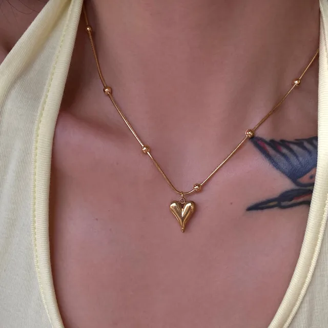 Lilyah Jewelry Necklace. Gold necklace with a heart pendant on a person wearing a beige top.