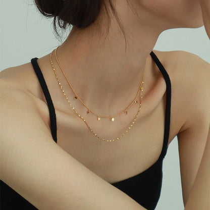 A person wearing a black tank top and a double-layered gold-plated necklace with a diamond-shaped pendant. Lilyah Jewelry Gold Plated Necklace. Gift Ideas for her.