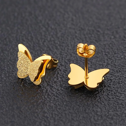 A pair of 18k gold plated butterfly stud earrings on a dark surface. Lilyah Jewelry Gold Plated Earring. Gift Ideas for her.