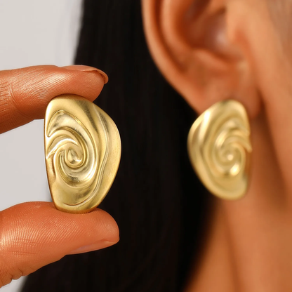 A close-up image of a person's ear wearing a gold-colored swirl design earring. Lilyah Jewelry Gold Plated Earring. Gift Ideas for her.