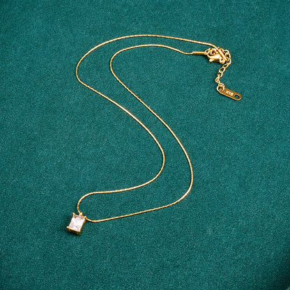 A gold-plated pendant necklace with a princess cut white diamond pendant on a titanium steel chain, displayed against a green background. Lilyah Jewelry Gold Plated Necklace. Gift Ideas for her.