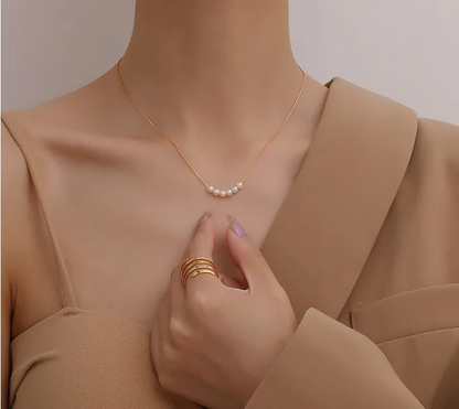 A person wearing a beige top showcasing a gold-plated necklace with artificial pearls. Lilyah Jewelry Gold Plated Necklace. Gift Ideas for her.