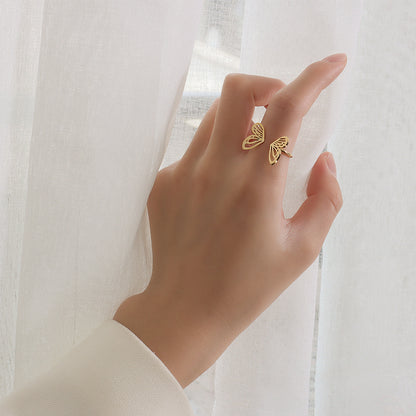 A person's hand wearing a gold-plated butterfly wing open ring, with the ring positioned against a white translucent fabric. Lilyah Jewelry Gold Plated Ring . Stunning, minimalistic, adjustable, elegant and statement ring. Gift idea for her.