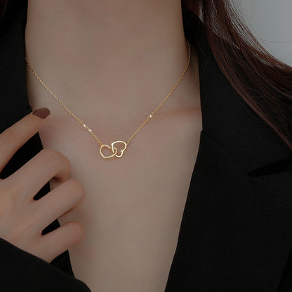 A gold-plated necklace with a linked hearts pendant, worn by a person in a low neckline black dress. Lilyah Jewelry Gold Plated Necklace. Gift Ideas for her.
